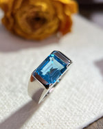 Lifestyle photography of Emerald cut blue topaz statement ring featuring Emerald Cut center stone
