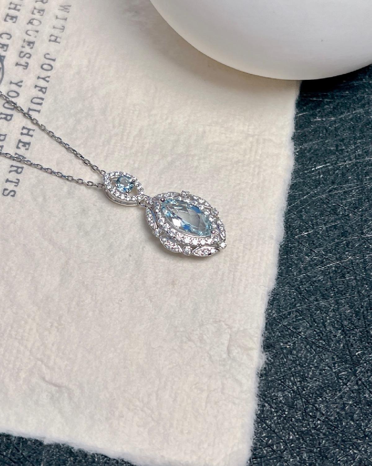 On-hand shot of Marquise cut aquamarine halo necklace featuring Marquise Cut center stone