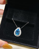 Lifestyle photography of Pear cut blue topaz halo necklace featuring Pear Cut center stone